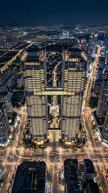 Aerial High-Angle Shot of Symmetrical Twin Skyscrapers in a Glowing Night City - Free mobile Wallpaper