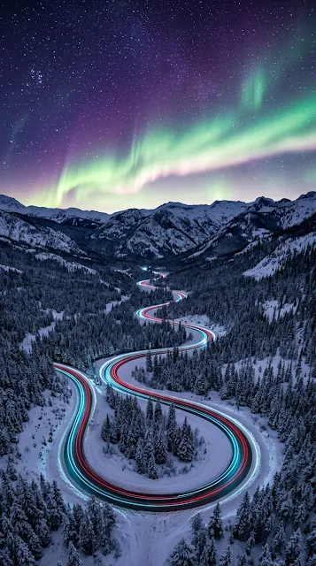 Aerial Snowy Mountain Highway beneath Northern Lights Aurora Wallpaper - Free 4K & 8K mobile Wallpaper