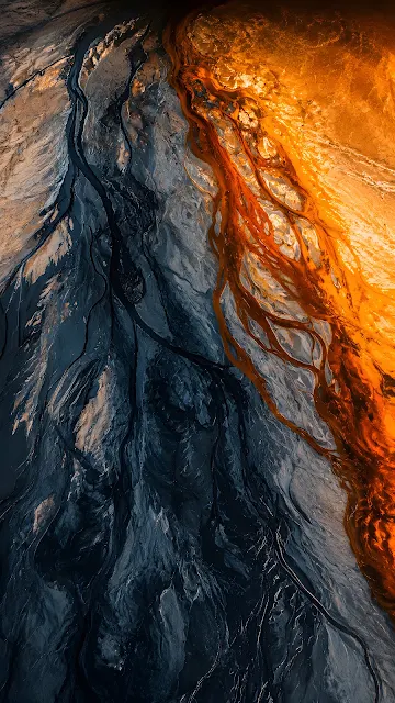 Aerial view of a braided river estuary showing intricate bright orange sediment channels flowing beside dark slate blue water.
