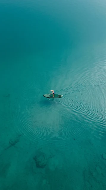 Aerial View of Lone Paddleboarder on Turquoise Lake - Free 4K & 8K mobile Wallpaper