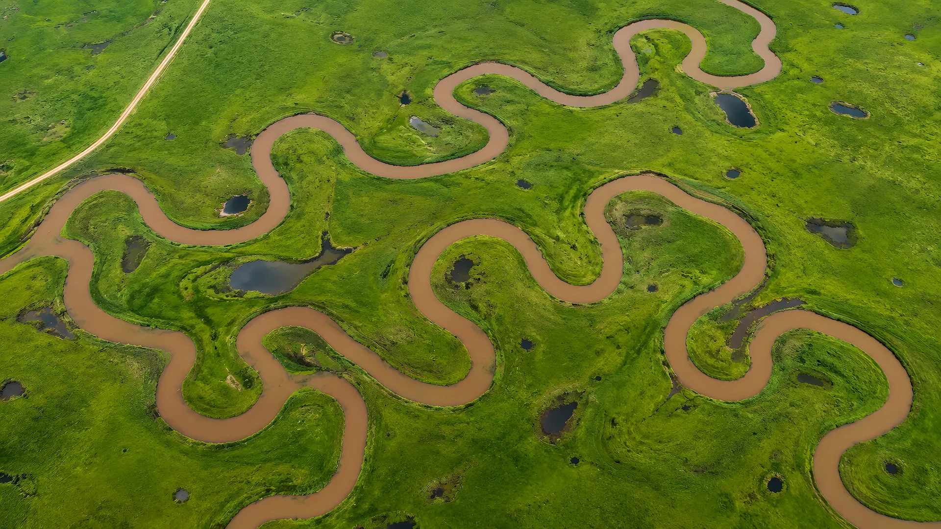 Aerial view of a winding river looping through green plains - Free 4K desktop Wallpaper