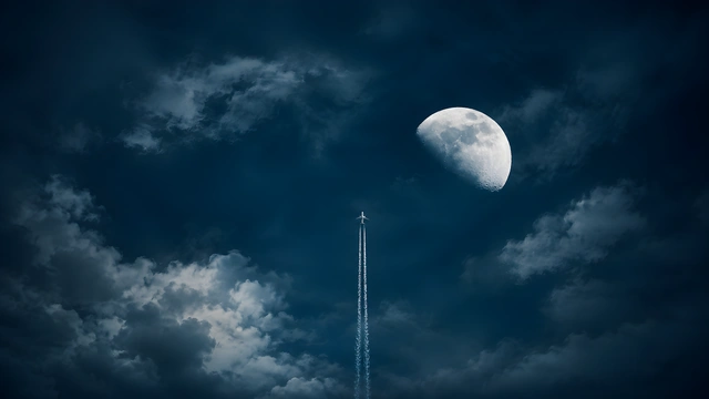 Airplane ascending vertically with a white contrail next to a bright moon in a dark cloudy night sky.