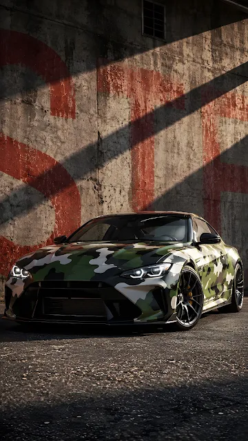 A green, white, and black camouflage wrapped performance sports car parked alongside a weathered concrete wall with red industrial painted lines.
