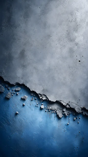 Close-up of a broken grey concrete wall peeling away diagonally to reveal a textured bright blue layer beneath.