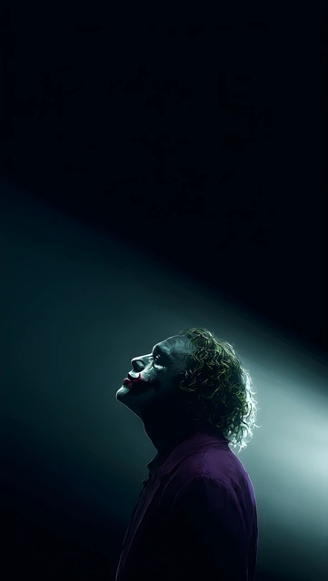 Side profile of The Joker looking up toward a bright spotlight against a dark background.
