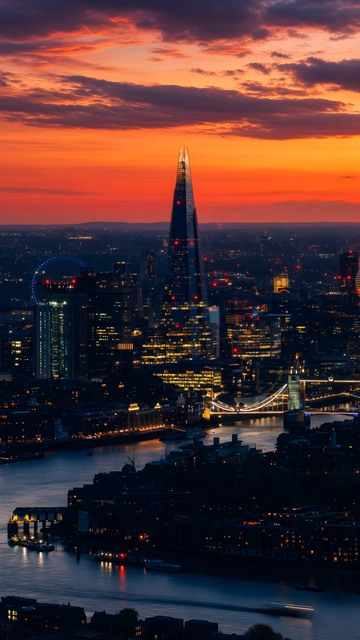 Aerial view of The Shard, Tower Bridge, and River Thames under a red and orange twilight sky.
