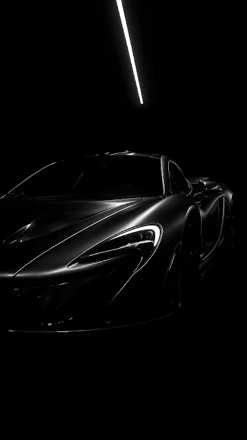 A futuristic matte-black hypercar positioned in a dark studio, with crisp white overhead lights outlining its aerodynamic body lines.