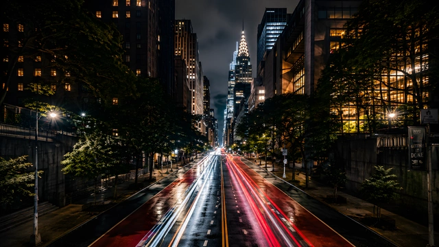 Long exposure photo of red and white car light trails on a New York City street facing the Chrysler Building.