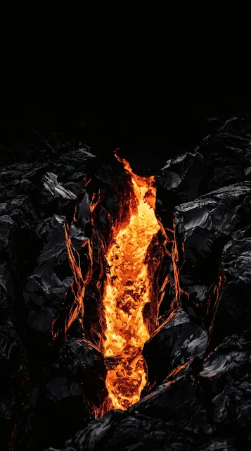 Glowing molten orange lava pulsing through sharp black obsidian rock fissures at night.