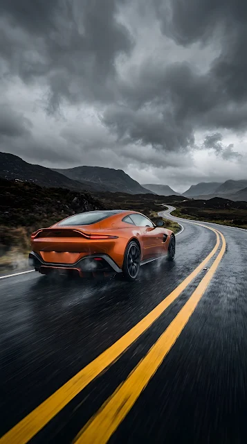 Orange High-Performance Sports Car on Dark Asphalt Road Under Stormy Clouds - Free mobile Wallpaper
