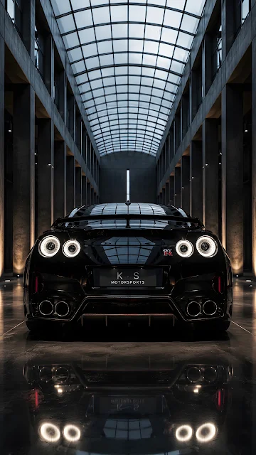 A clean rear-view rendering of a modern glossy black sports car with white circular taillights parked inside a monochrome columned hallway.