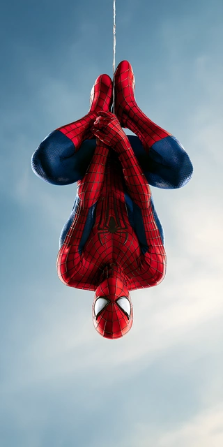 Spider-Man hanging upside down on a web line against a clear blue sky wearing a red and blue textured suit.