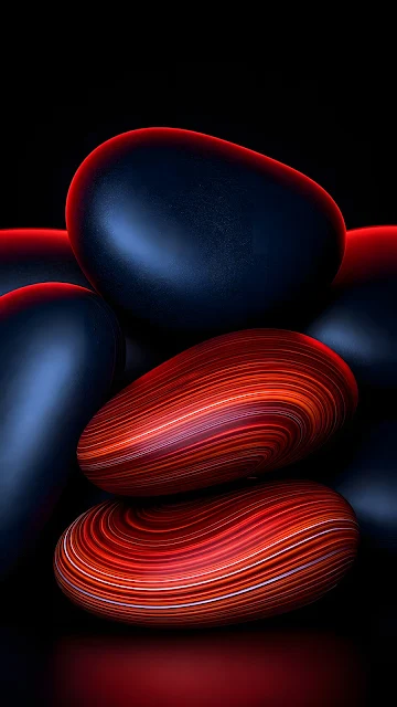 Stacked polished black river stones accented by two red and orange striated agate stones on a dark background.