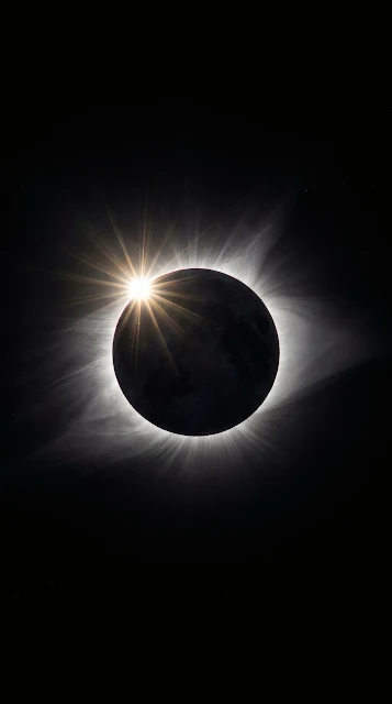 Total solar eclipse diamond ring effect with brilliant white solar corona flare against pitch-black cosmic space.