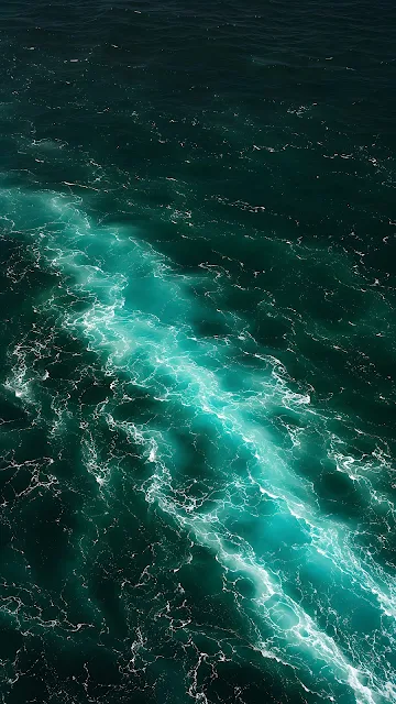 Turquoise ocean current cutting diagonally through deep emerald and black water.