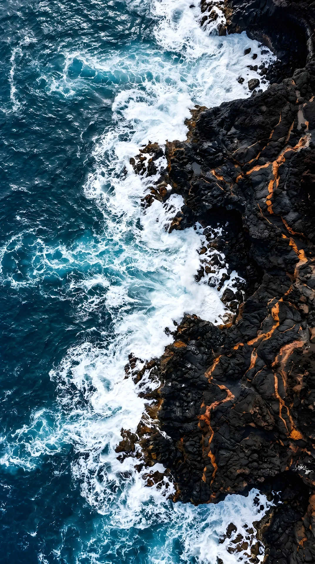 Vertical Aerial View of Black Volcanic Rock Meeting Deep Blue Ocean - Free 4K mobile Wallpaper