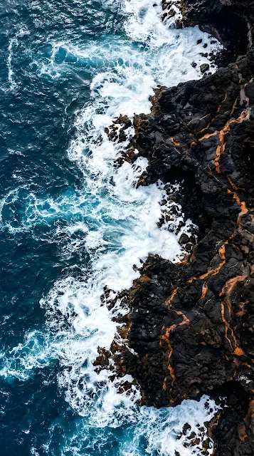 Vertical Aerial View of Black Volcanic Rock Meeting Deep Blue Ocean - Free mobile Wallpaper