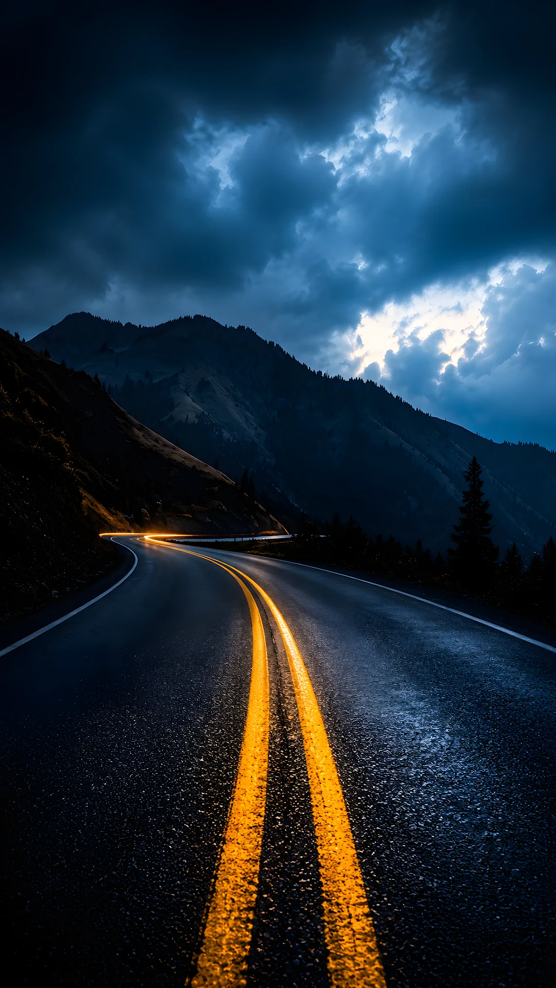 Winding Mountain Highway with Golden Light Trails Under Stormy Night Sky - Free 4K mobile Wallpaper